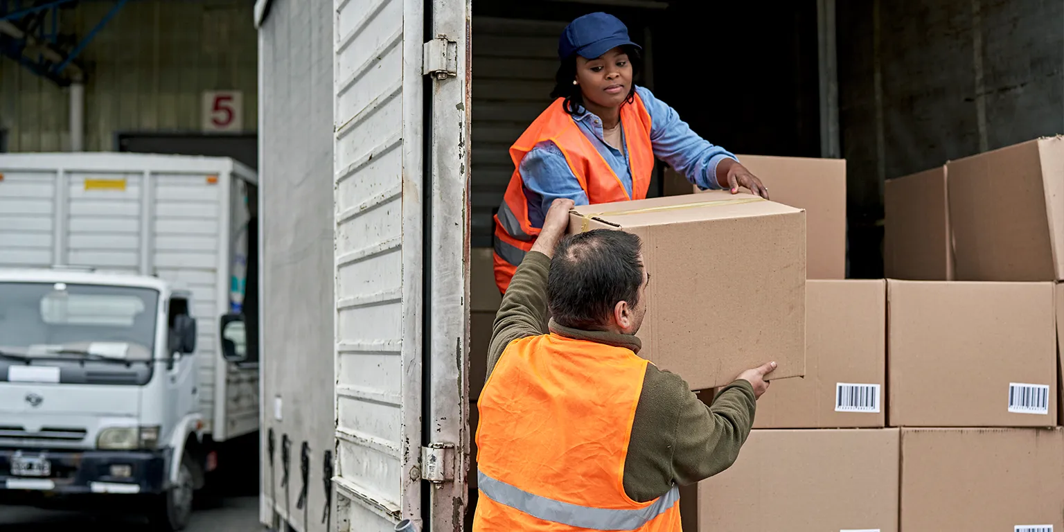 Two workers loading boxes into a lorry