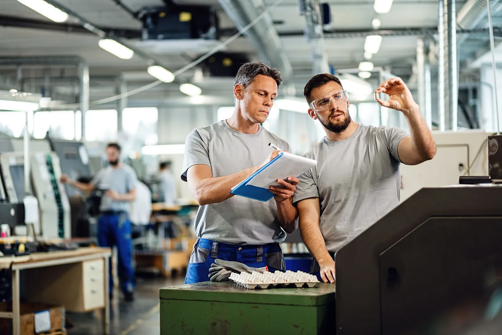 Two men reviewing a clipboard on a factory floor